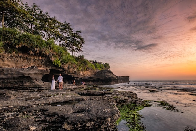 Los amantes están viendo una bandada de murciélagos desde una cueva en la costa al atardecer