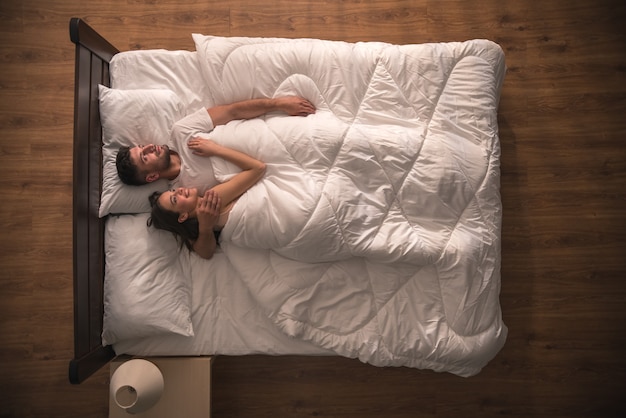 Foto los amantes felices se abrazan en la cama. vista desde arriba