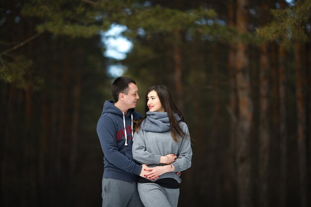 Amantes felices en invierno en el fondo del bosque nevado al aire libre