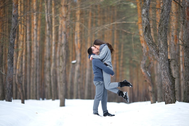 Amantes felizes no inverno no fundo do bosque nevado ao ar livre