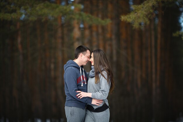 Amantes felizes no inverno no fundo do bosque nevado ao ar livre