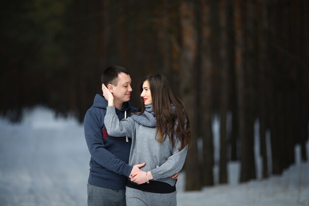 Amantes felizes no inverno no fundo do bosque nevado ao ar livre