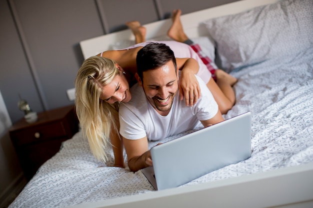 Amantes íntimos usando laptop deitado na cama no quarto