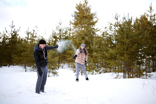 Amantes jogando neve uns nos outros brincando de felizes e alegres