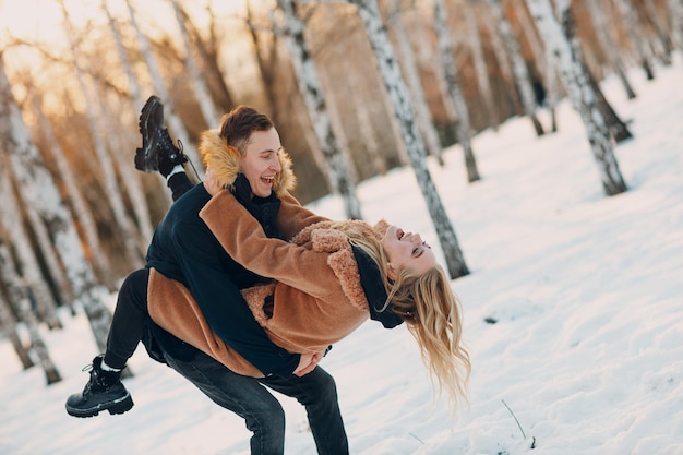 Amantes de la joven pareja amorosa abrazándose y divirtiéndose en las citas de Winter Forest Park.