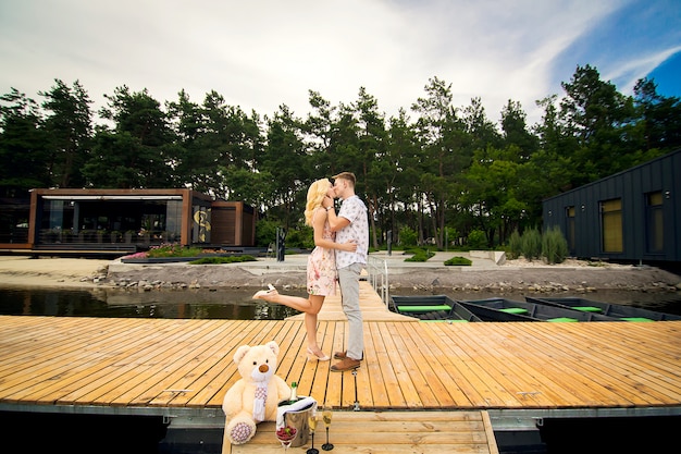 Amantes de la joven pareja besos en un muelle de madera. Lovestory en el muelle