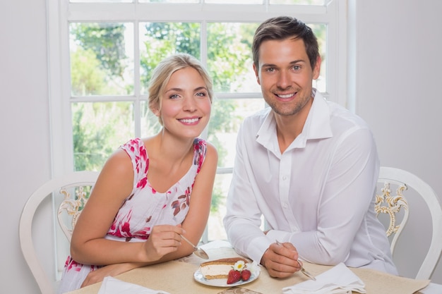 Amantes de la joven pareja con pasteles en la mesa de comedor