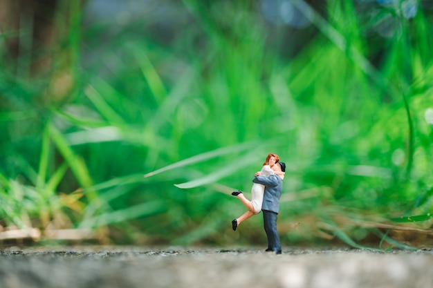 Los amantes de las miniaturas se abrazan en el fondo de la naturaleza verde utilizando como concepto de familia y amor