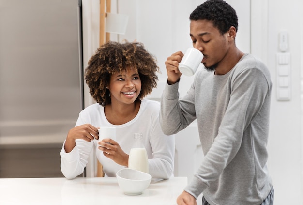 Amantes negros felizes bebendo café na cozinha conversam