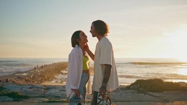 Amantes románticos besándose al amanecer patinadores de playa pareja mirando el horizonte del mar