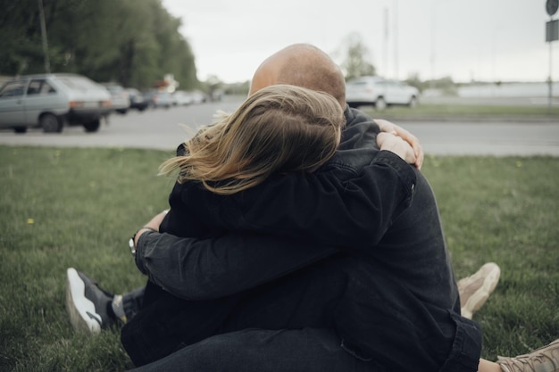 Amantes se abraçam firmemente sentados na grama