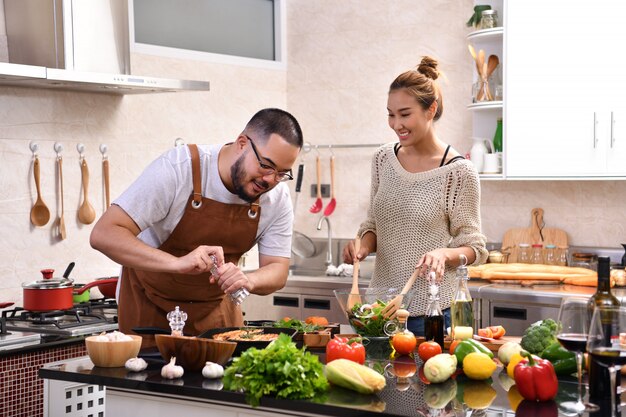 Amar o jovem casal asiático cozinhando na cozinha, fazendo comida saudável juntos, sentindo-se divertido