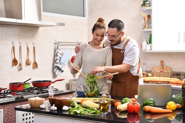 Amar o jovem casal asiático cozinhando na cozinha, fazendo comida saudável juntos, sentindo-se divertido