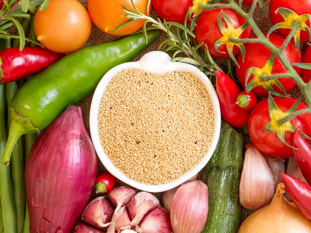 Amaranto orgánico crudo en un tazón entre vista superior de verduras crudas