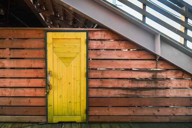 Amarillo puerta de madera cerrada con llave bloqueada en tablones de madera tiras de pared de la habitación debajo de las escaleras