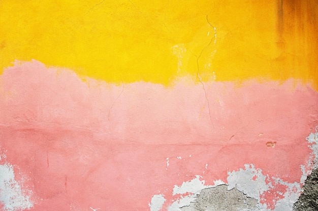 Amarillo, rosa, gris yeso destruido en una pared de ladrillos. Grunge cemento, con un fondo de pintura en mal estado.