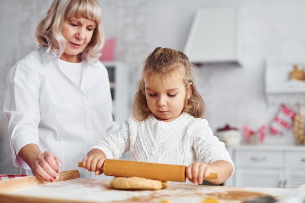 Amasa la masa La abuela mayor con su nieta cocina dulces para Navidad en la cocina