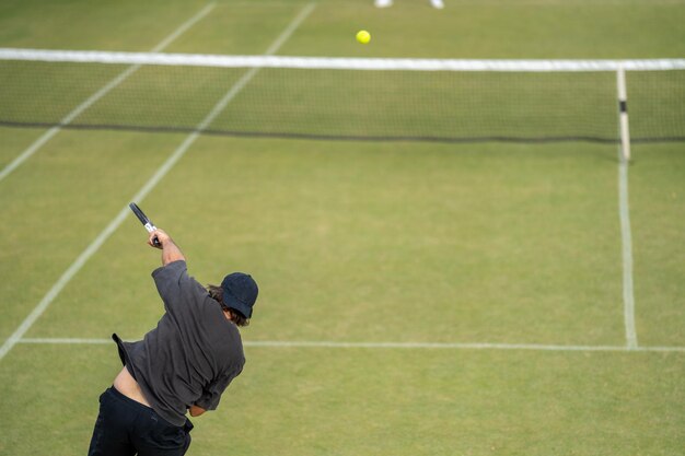 Foto amateur jugando al tenis en un torneo y partido sobre césped en europa