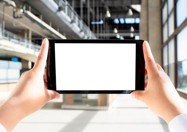 Foto ambas as mãos seguram um tablet o ecrã do tablet é com um fundo branco