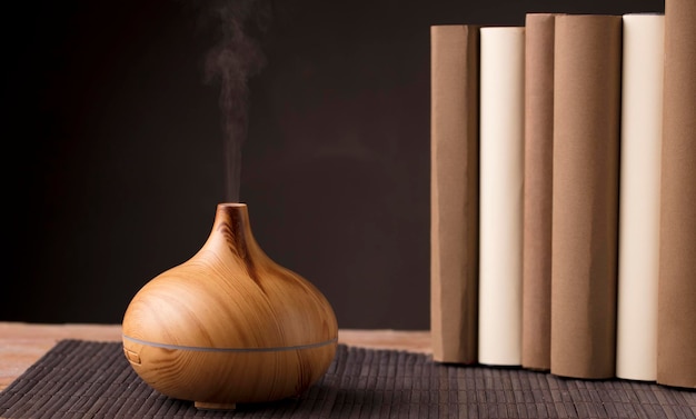 Foto ambientador de óleo essencial em madeira com livros no fundo marrom da mesa