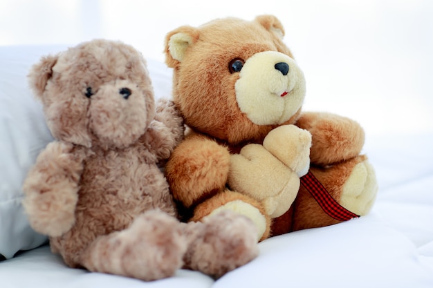 Ambiente romántico y placentero en el dormitorio creado por el concepto de dos hermosos ositos de peluche marrones y esponjosos colocados creativamente cerca como un dulce amigo que actúa en juegos divertidos