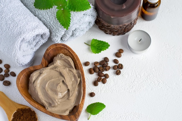 Ambiente de spa con mascarilla cosmética de arcilla para el cuerpo, aceite esencial de toalla y granos de café