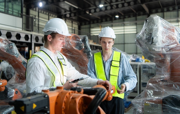 Ambos ingenieros trabajan juntos en una fábrica de brazos robóticos Industria e ingeniería de brazos robóticos