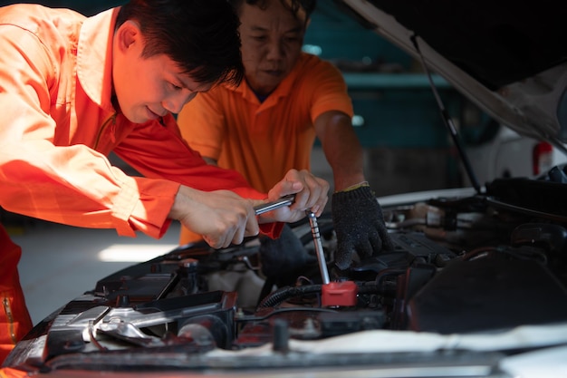 Ambos mecánicos de automóviles están inspeccionando el motor del automóvil de un cliente que se está llevando para repararlo en un garaje.