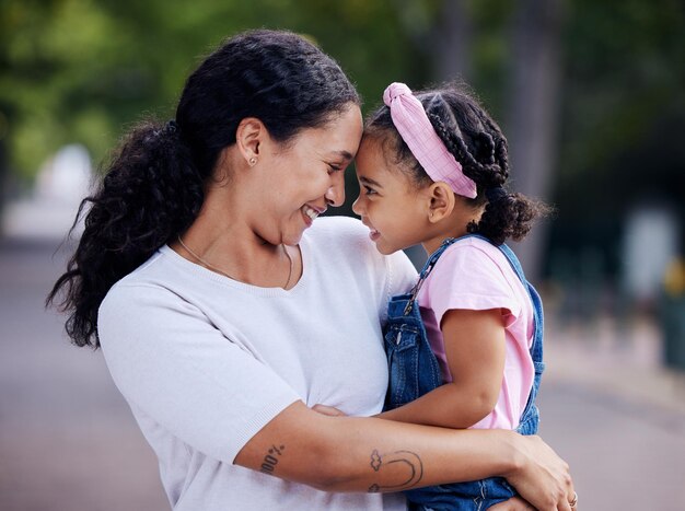 Ame a família e a mãe carregando a menina ao ar livre, unindo e abraçando cuidados de apoio à maternidade e mulher abraçando ou abraçando a filha ou criança e aproveitando o tempo de qualidade juntos no parque