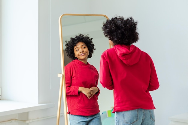 Ame-se linda jovem sorridente mulher afro-americana dançando apreciando seu reflexo no espelho