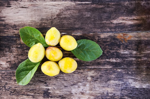 Ameixas amarelas. frutas doces maduras frescas em fundo áspero de tábuas de madeira velhas.