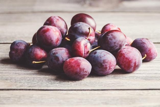 Ameixas em uma pilha na mesa de madeira colhidas frutas de ameixa no espaço de cópia de outono