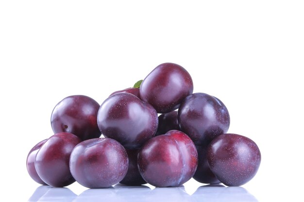 Ameixas frescas maduras deliciosas empilhadas em um fundo branco isolado