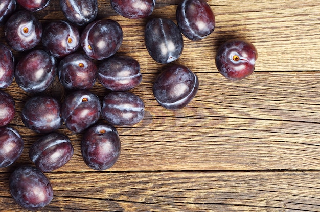 Ameixas maduras violetas em fundo de madeira