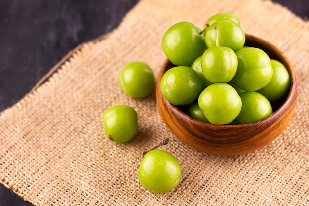 Ameixas verdes verdes em uma mesa de madeira preta