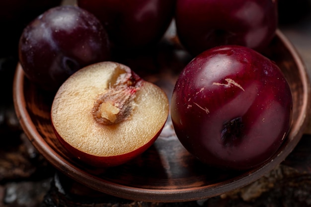 Ameixas vermelhas fatiadas frescas em um fundo escuro de madeira