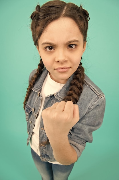 Amenazar con el puño niño enojado agitar el puño fondo gris aspecto de belleza de niña niño pequeño en ropa casual estilo de moda cuidado infantil e infancia día internacional del niño