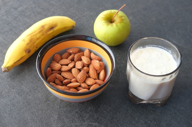 amêndoa noz banana maçã e leite na mesa