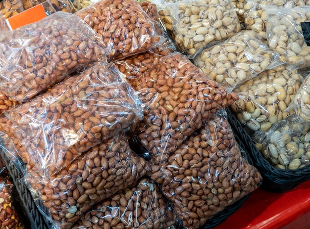 Amendoim e pistache naturais acondicionados em sacos plásticos e vendidos na loja. as castanhas já estão na prateleira e prontas para serem vendidas no mercado. dieta, alimentação saudável. comida saudável.