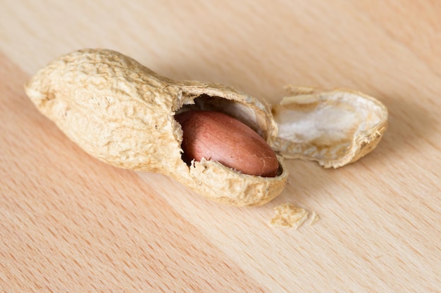 Foto amendoim meio descascado com casca rachada em uma mesa de madeira