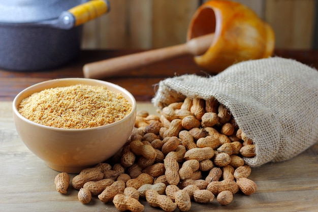 Amendoins triturados e moídos em tigela de cerâmica formando farinha na mesa de madeira rústica alimentos orgânicos