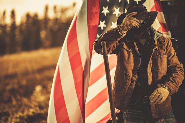Foto american cowboy rancher na frente da bandeira nacional dos estados unidos