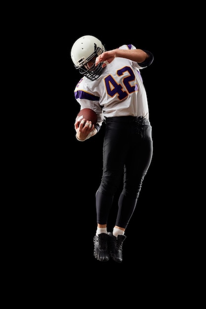 American-Football-Spieler in Uniform mit dem Ball bereitet sich darauf vor, einen schwarzen Hintergrund des American-Football-Konzepts zu passieren