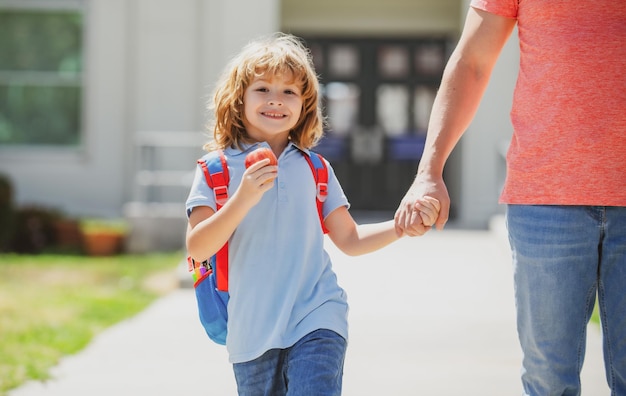 American padre e hijo caminando por el parque escolar primer día en la escuela padre lleva a un niño pequeño s