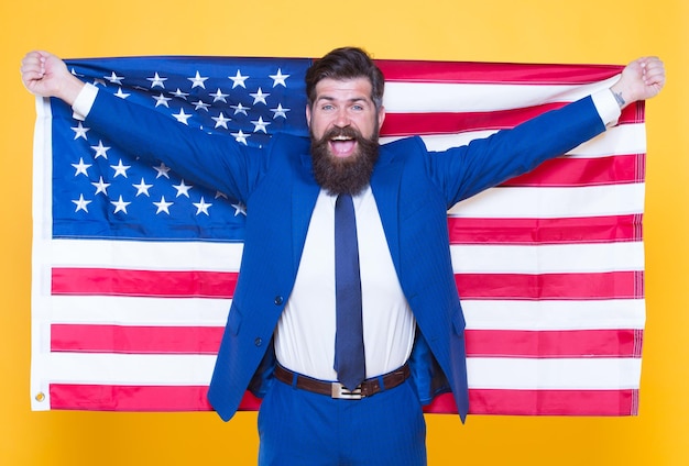 Americano por nacimiento Rebelde por elección Concepto de hombre de negocios Hombre de negocios confiado guapo hombre barbudo en traje formal sostener bandera EE. UU. Hombre de negocios exitoso apariencia bien arreglada Gente de negocios