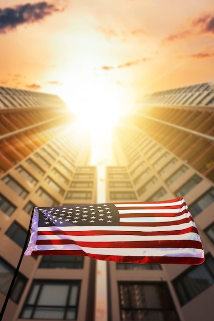 Amerikanische Flagge weht in der Luft mit Wolkenkratzern Hintergrund. Konzept für den vierten Juli