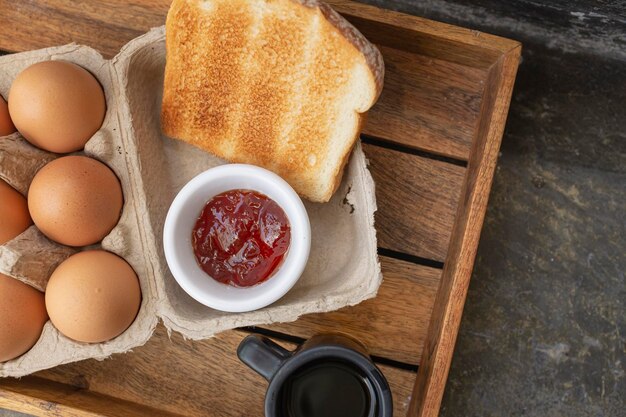 Amerikanische Frühstückszutaten mit roten Eiern auf einem Holztablett