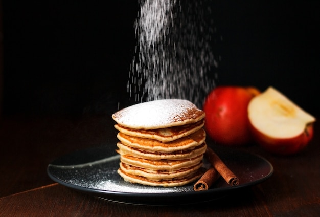 Amerikanische Pfannkuchen mit Zimt und Äpfeln auf dunklem Hintergrund