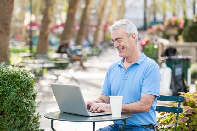 Amerikanischer älterer Mann mit Computer am Park