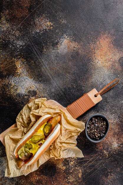 Amerikanischer Hotdog mit Schweinefleischwurst auf einem hölzernen Schneidebrett in Kraftpapier